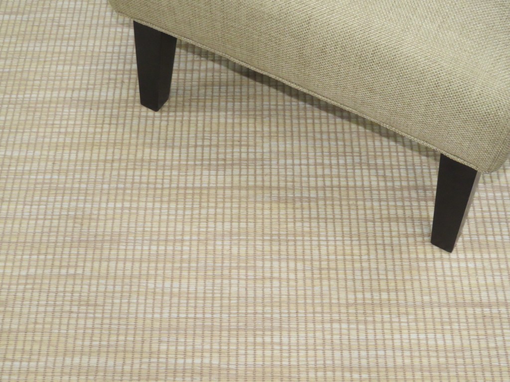 Bellbridge Grasscloth Sea Stone 5205/920 shown with chair used as prop. Grasscloth is a textured loop pile wilton fabricatd with striated yellow/camel yarns as the background and solid yarns that create a linear design.