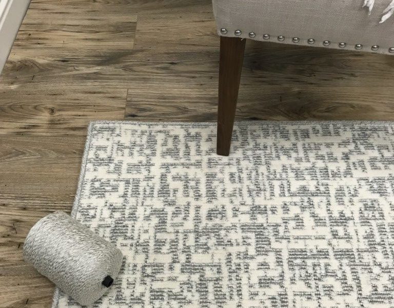 Impressions, Color: Stelvio/White 20/8007 serged rug featured with complementary serging yarn and chair. Impressions is a cut/loop wilton fabricated with 2 colors of yarn (lt blue,white). The cut pile creates a graphic textural design.