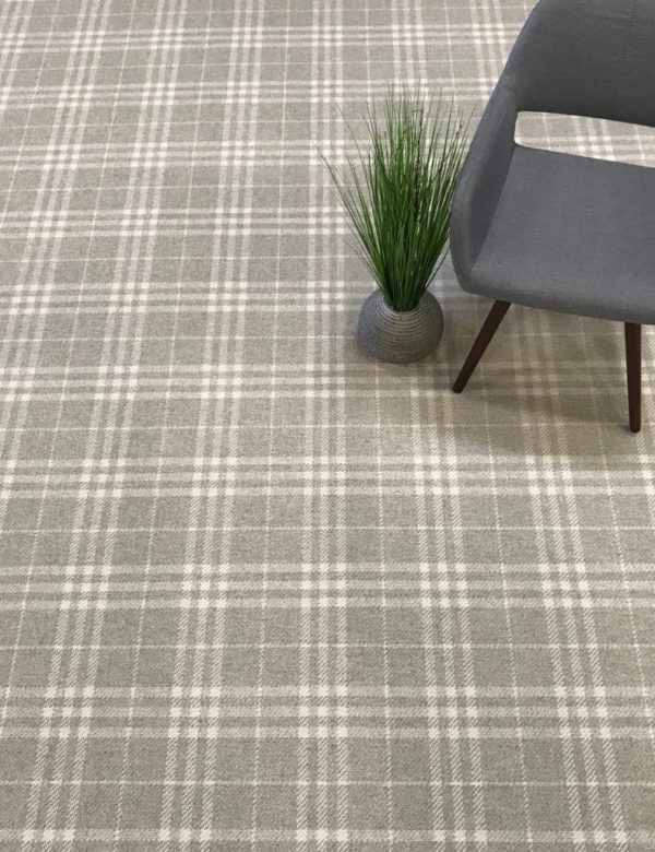 Glencoe, Color: Stonewash 1022F/5712F shown with props. Glencoe, Color: Stonewash 1022F/5712F shown with chair and faux plant as props. Glencoe is flatwoven plaid design with 2 colors (grey and white).