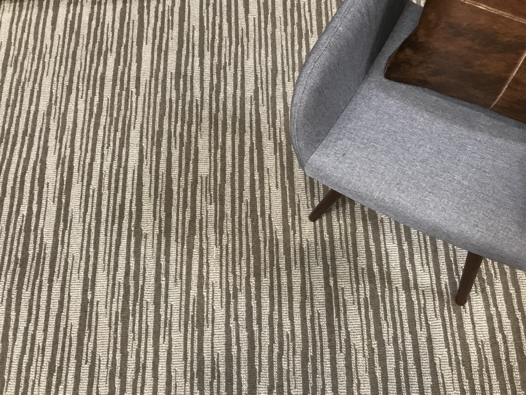 Capella, Color: Cosmic Dust 44/5522 shown with chair as prop. Capella is a cut/loop pile wilton carpet using two colors designed to create a staggered linear design.