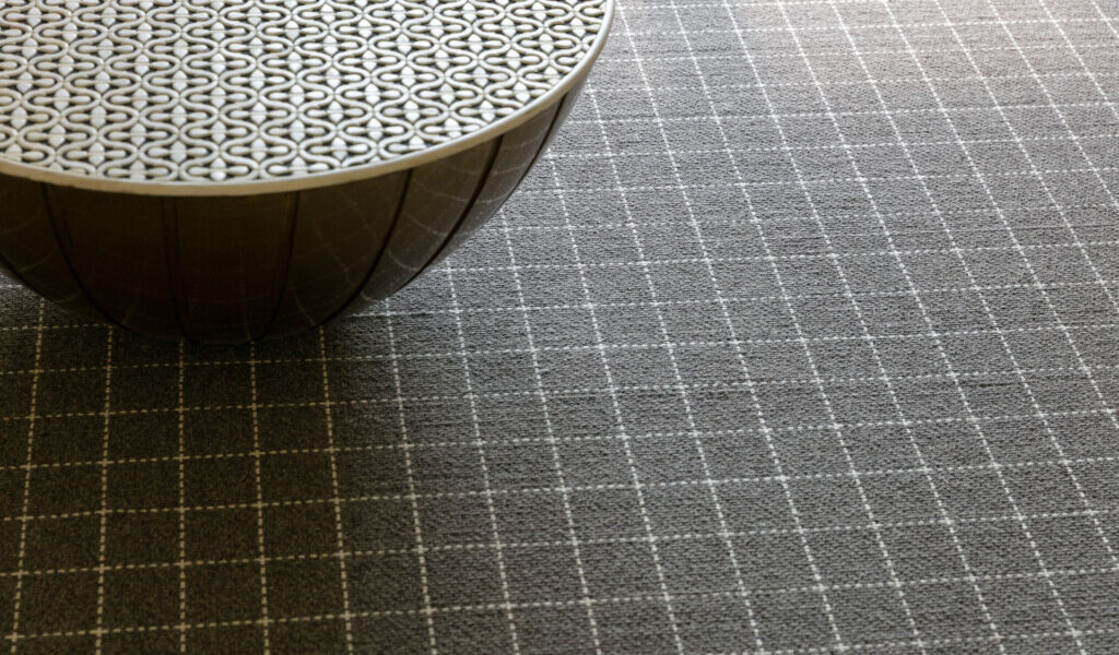 City Block, Color: Granite/Ivory 700/1506 shown with table.City Block is hand loomed with two colors of heathered yarns creating a block design.