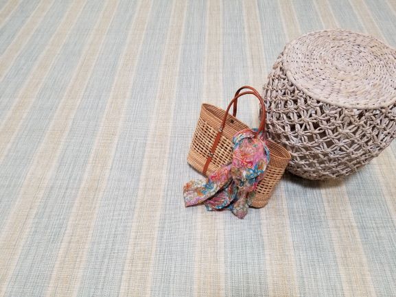 Linen Stripe, Color: Aqua Sand 370F / 5703F showing tote and basket as props. The stripe pattern runs vertically down the length of the carpet. This colorway is available in 15'9" width.