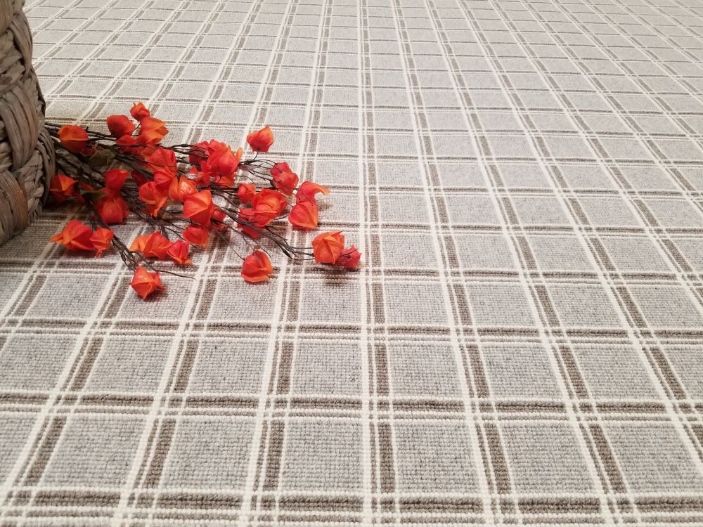 Logan, Color: Gable Grey 29/5760 shown with flowers as prop. Logan is comprised of three different colored yarns (lt grey, lt taupe and natural white) woven across the warp and weft to create a tailored grid design.