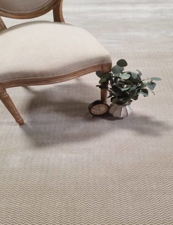 Empire, Color: Beige 1/1603 shown with props Empire, Color: Beige 1/1603 shown with chair and plant as props. Empire is a cut/loop carpet that has a zigzag (chevron) pattern.