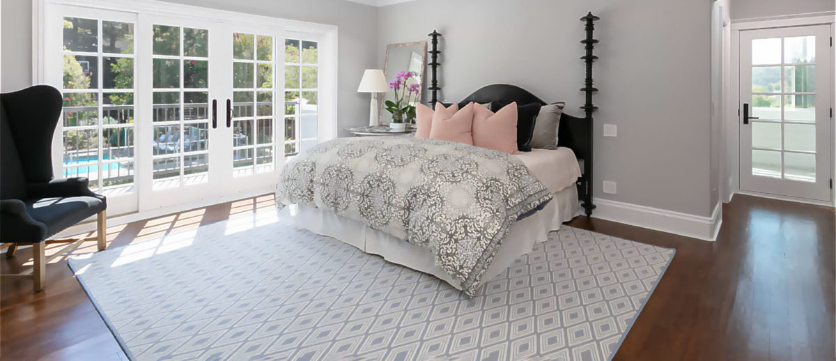 Ava, Color: Blue Mist 7/8012 fabricated rug in bedroom with furnishings. Ava has a repetitive, textural diamond pattern created with two yarn colors (blue and natural white). Image credit: The Beaubelle Group, Orinda, CA